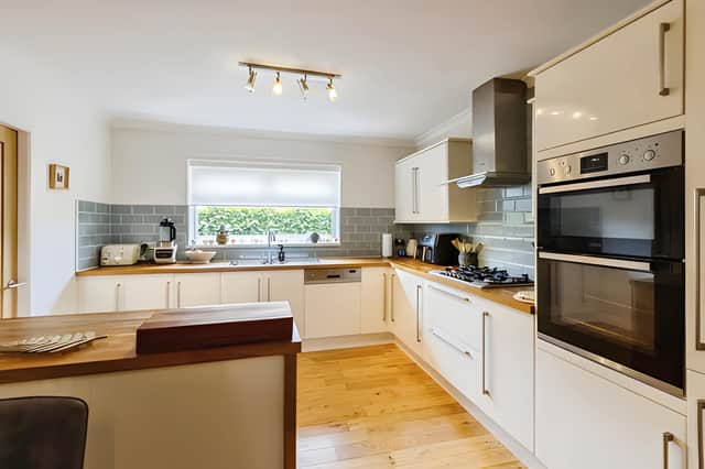Solid wood worktops, a five-ring gas hob and double electric oven feature in the modern kitchen and dining room