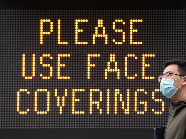 File photo of a man wearing a protective face mask walking past signage advising the use of face coverings.
