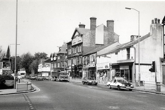 Headingley Lane from Hyde Park Corner. The junction with Hyde Park Road is on the left. On the far right is the edge of The Hyde Park pub. Shops following on from this include Snipperfields Circus hairdressers, a cane furniture and basketware store and La Paprika coffee bar.