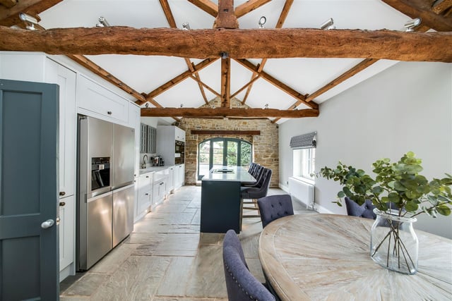 The absolutely stunning open-plan dining kitchen is sure to impress with fabulous open height ceilings which display timber trusses and beams. There is an exposed stone wall to the front elevation with barn arched French doors which lead to the front courtyard.