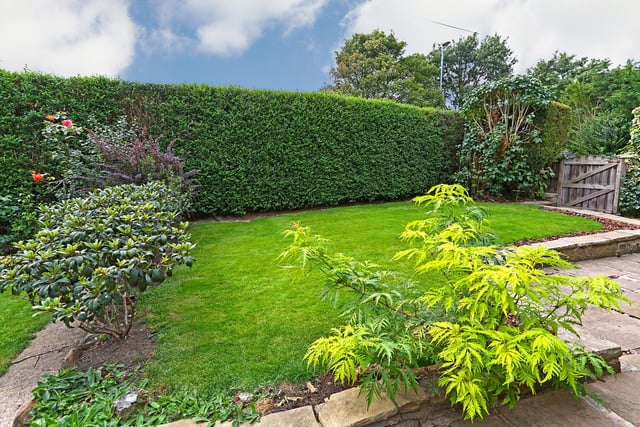 A hedge and low stone walls surround this shaped lawn.