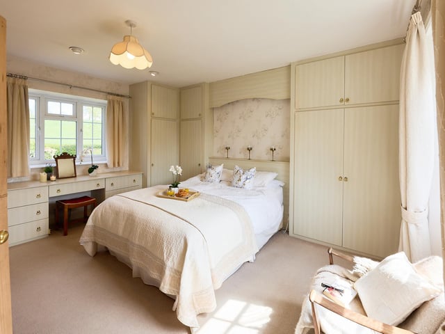 This bedroom with a countryside view has fitted furniture.
