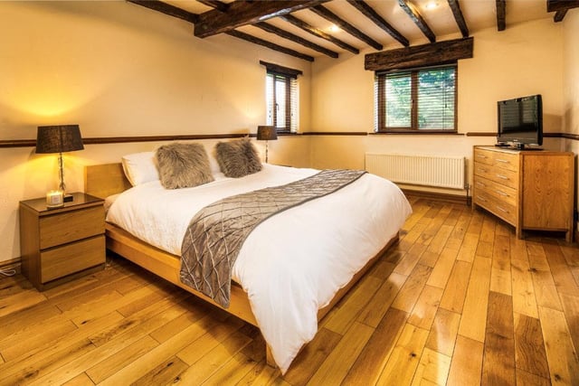 One of the spacious beamed bedrooms, with double aspect windows and wooden flooring.