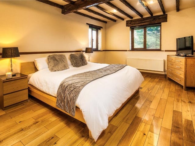 One of the spacious beamed bedrooms, with double aspect windows and wooden flooring.