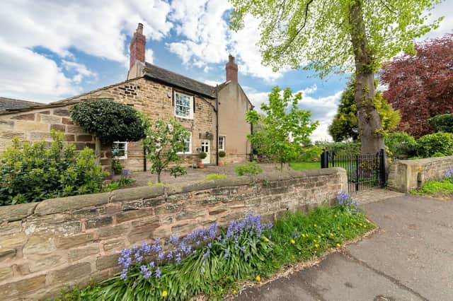 Gates between stone walls lead in to the attractive stone property in its leafy village on the outskirts of Wakefield.