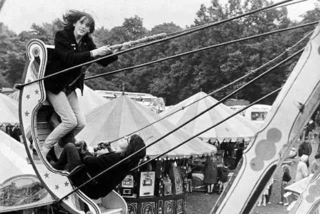 Two park visitors swing over the heads of the crowds at a fair held in Clarence Park in 1965.