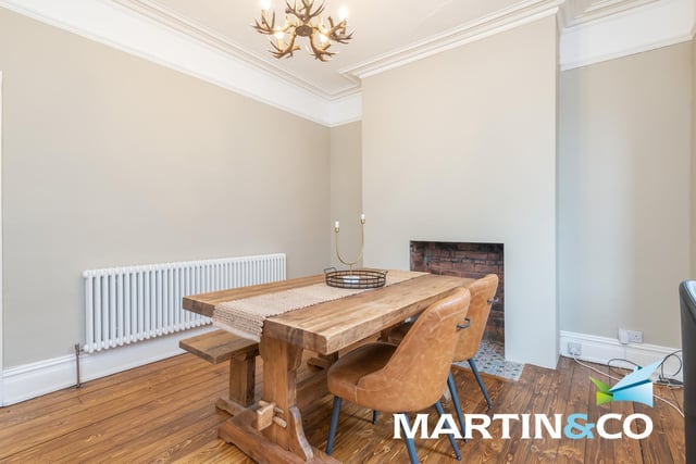 A natural wood floor and a chimney breast feature are in the dining room, that is well lit by a bay window.