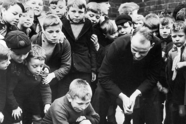 A crowd of pupils of Whitwood Mere School in Castleford, Yorkshire, watching a fellow pupil competing in a game of marbles. The winner will represent the school in an inter-school match on Shrove Tuesday.