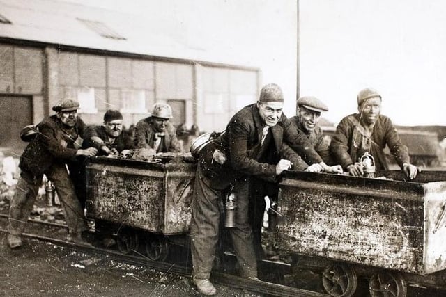 A group of miners who are members of the Castleford Rugby League team, at work on their coal tubs at the mine. The tubs make excellent practice for scrum work, and the team are famed for their powers in the scrum.