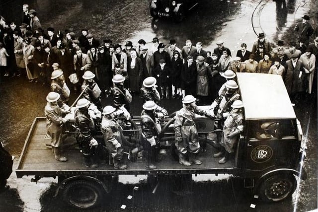 Crowds watch the Auxiliary Fire Brigade pass by on their lorry, during a procession through Wakefield. Herbert Sutcliffe is taking part in a National Service recruiting campaign, which concluded at the Town Hall with an address by Herbert Sutcliffe, Mr Arthur Greenwood MP, and the Mayor of Wakefield.