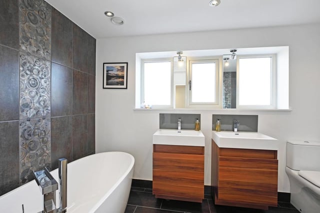 Twin washbasins with vanity units are a feature of this modern house bathroom, with a free standing, deep bath tub.