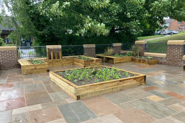The garden features raised plant beds and areas for people to sit and relax.