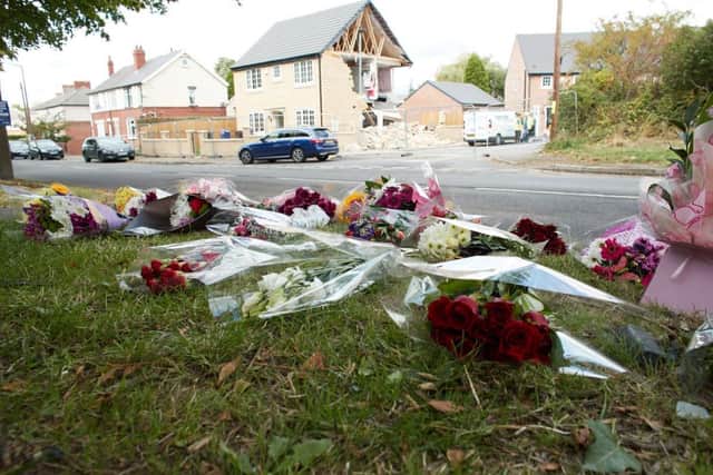 Flowers left at the scene where Jackie died, with the wrecked house in the background.