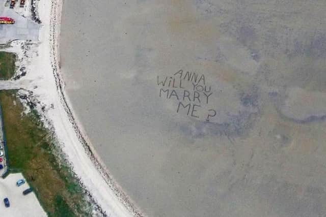 Jamie's proposal was written in the sand as they approached the beach.
