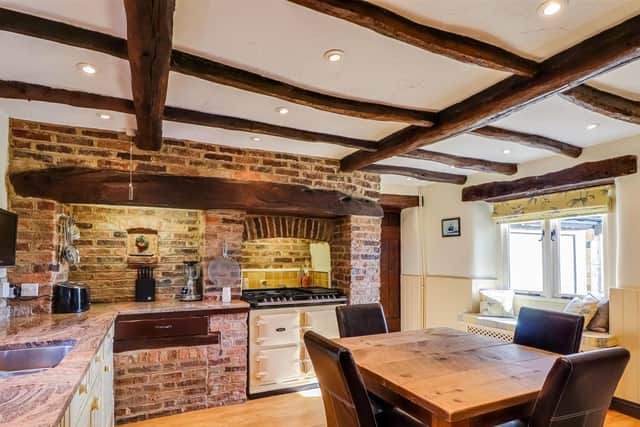 A farmhouse style kitchen with beams and exposed brickwork.