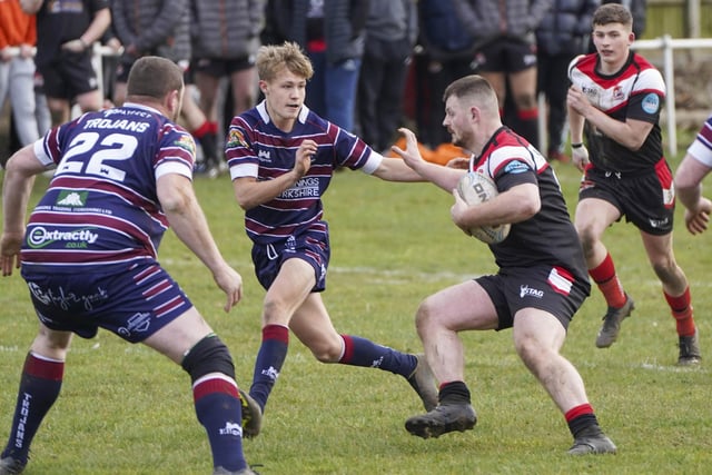 Fryston Warriors look for space with Thornhill Trojans' James Stanley (number 22) measuring up for a tackle.