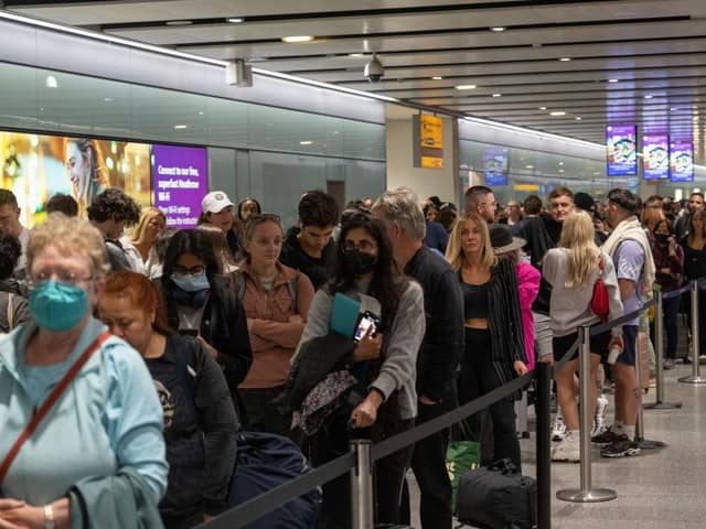 Travellers wait in a long queue to pass through the security check. (Photo by Carl Court/Getty Images)