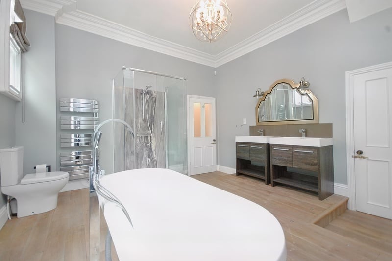 A palatial bathroom with twin wash basin vanity units.