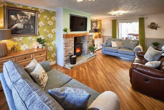 An open brick fireplace with Yorkshire stone hearth, housing a log burner, is a feature in the lounge.