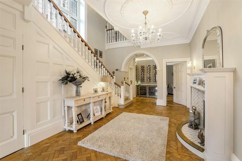 The entrance vestibule leads to a stunning reception hallway with an original polished wood floor and fireplace, a display wine cabinet, a useful understairs storage and an impressive open staircase.