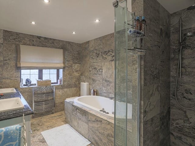 A tiled bath and shower room with twin washbasins.