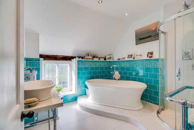 The house bathroom includes a free standing, roll top bath with chrome mixer tap and shower attachment, along with a Mosaic tiled corner shower cubicle with mixer shower. A ceramic wash basin is set on a marble work surface with chrome stand.