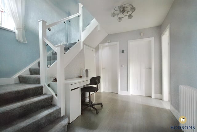 The roomy hallway leads to three bedrooms and a bathroom, with a staircase to the first floor.