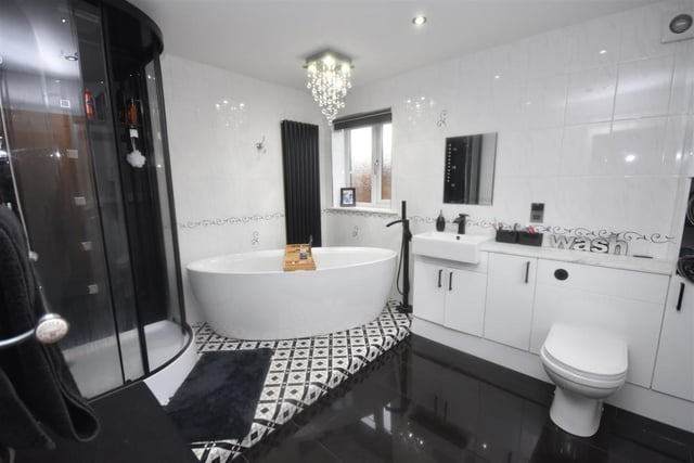 A stylish bathroom with a free standing bath, a corner shower cubicle and a built in vanity unit with storage.