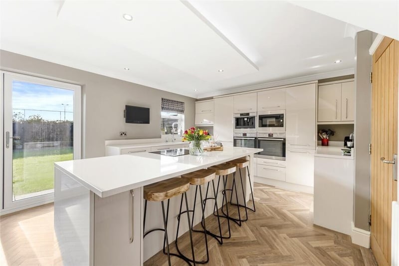 The kitchen is modern and well-appointed, with high quality fixtures and fittings. It offers ample storage space, sleek countertops, and a central island that serves both as a practical workspace and a casual dining area.