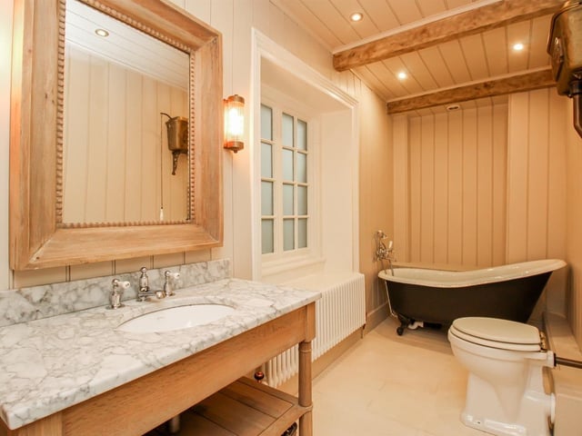 The family bathroom has an inset ceramic wash basin and mixer tap, with storage beneath, and a fired earth roll top bath with a Lefroy brooks mixer tap and shower attachment.