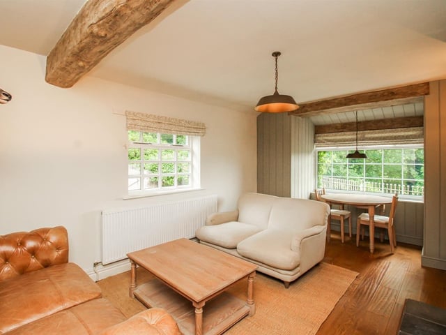 This reception space has exposed ceiling beams, decorative wall panelling and a multi-fuel burning stove set within a stone fireplace and hearth.