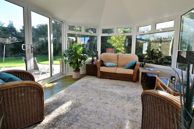 A lovely sun room is surrounded by garden.