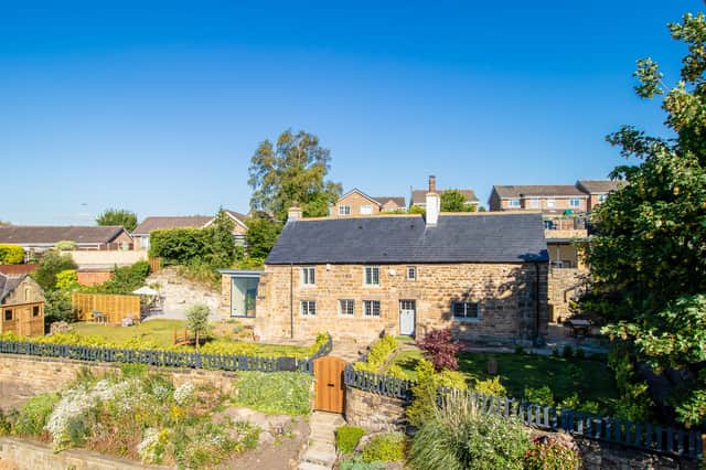 Attractive gardens surround the property, with a gated pathway leading to the door.