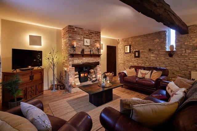 A cosy, rustic lounge with exposed stone wall and feature fireplace.