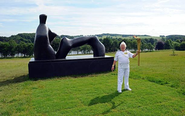 Eighty one year-old Muriel Brown from Manchester, carries the Olympic Flame to the Henri Moore sculpture in the Yorkshire Sculpture Park near Wakefield in, northern England, on June 25, 2012 as part of the 2012 London Olympic Torch Relay. Muriel was selected through the Coca-Cola campaign for her 60 years service to Amateur Athletics Coach and Judge Competitor Committees.  (Photo: PAUL ELLIS/AFP/GettyImages)