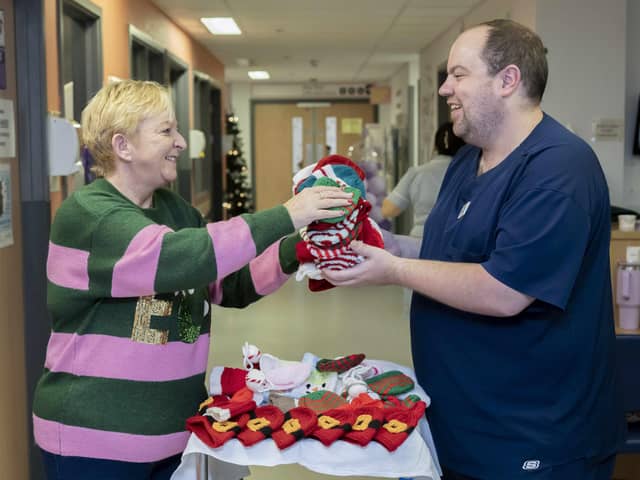 Susan Crossland donating knitted hats to ward manager Callum Douglass at the Neonatal Unit at Pinderfields hospital in Wakefield.