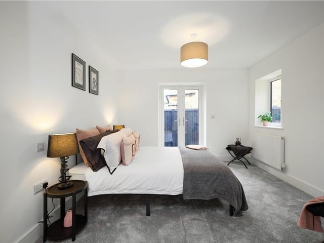 The spacious second double bedroom has French doors opening out to a private bistro patio and exposed beams retained from the original cottage.
