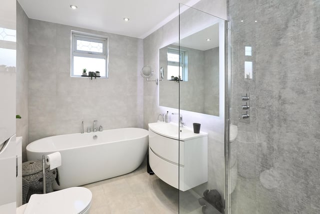 A contemporary bathroom with free standing bath, walk-in shower and washbasin vanity unit.