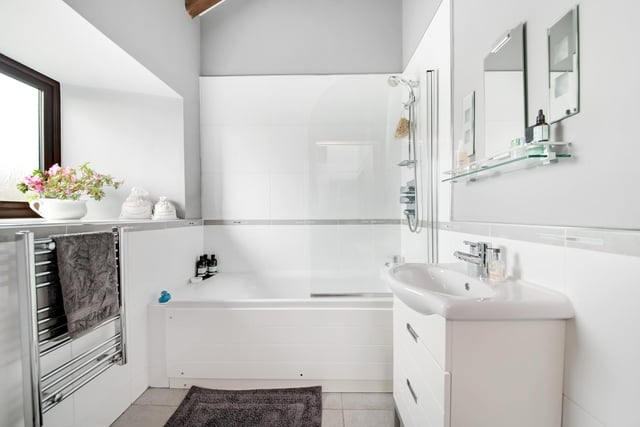 This bright and modern bathroom with white suite features both bath and shower.