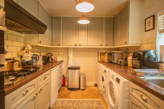 The kitchen is fitted with a matching range of painted oak fronted wall and base units, contrasting worktop areas, a stainless steel sink unit, a single drainer and a fitted oven and hob with an extractor hood over.