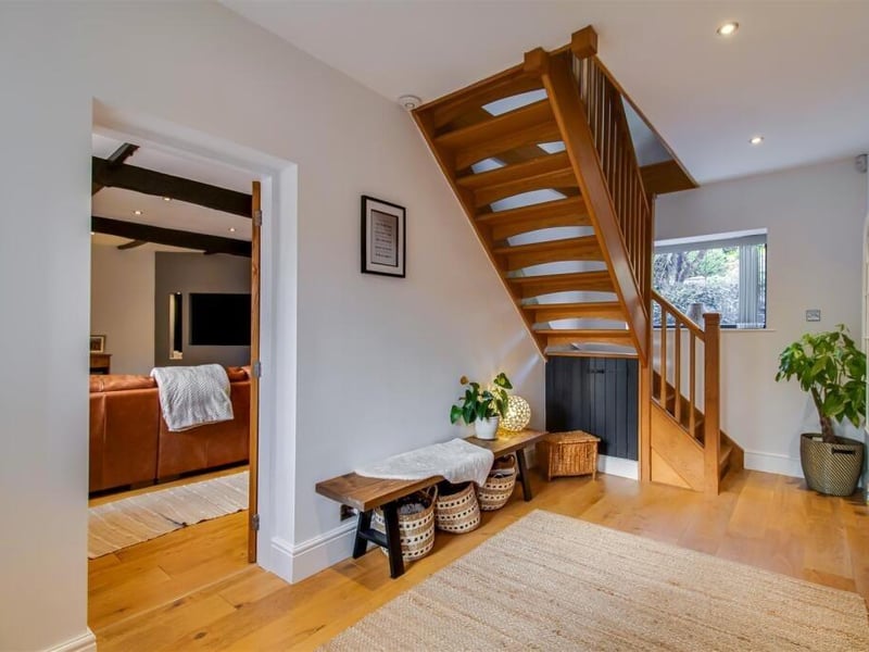 The main entrance hall features solid wood flooring, a solid oak balustrade staircase to the first floor landing, a UPVC double glazed window to the rear, recess ceiling spotlights and understairs storage.
