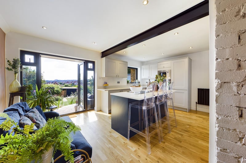 The open plan living kitchen opens out to a seating area with steps to the lawned garden.