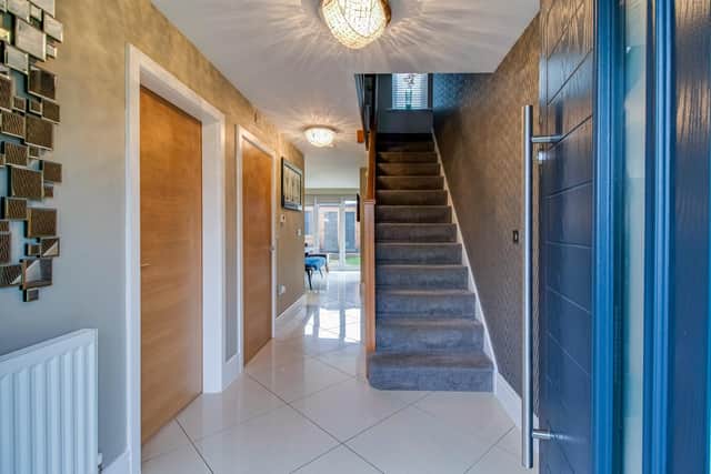 The hallway, with porcelain tiled floor, and feature staircase leading up.