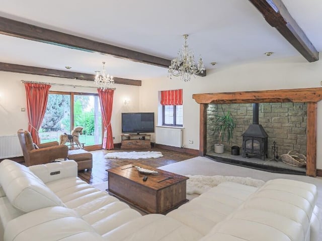 A beamed reception room with central feature fireplace and stove.