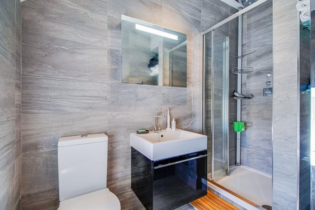 The en suite has a three piece suite comprising an enclosed shower cubicle with mixer shower, a vanity mirror with lighting, and a wash basin set in vanity drawer with chrome mixer tap. Other features include glass shelving and under floor electric heating.