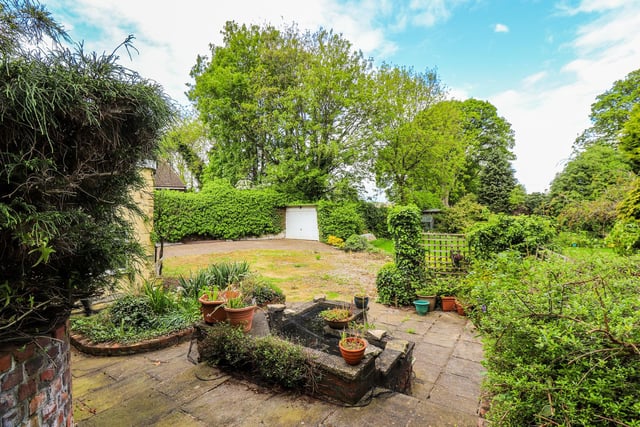 The property includes established and private lawned gardens with trees and shrubs.