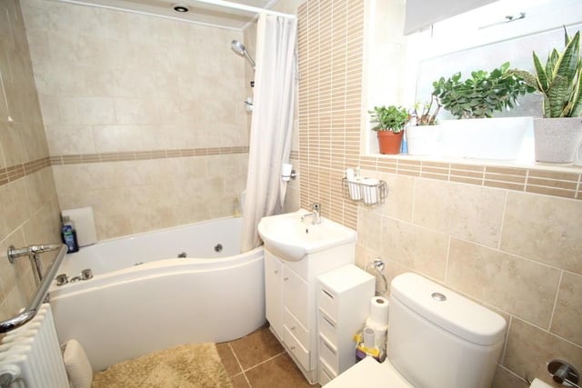 The bathroom has a white suite with a jacuzzi style bath and wash basin within vanity unit.