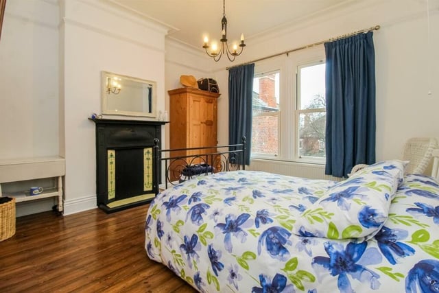 The primary bedroom features a central heating radiator, coving to the ceiling, a picture rail, a cast iron fireplace and a door leading to an en suite.