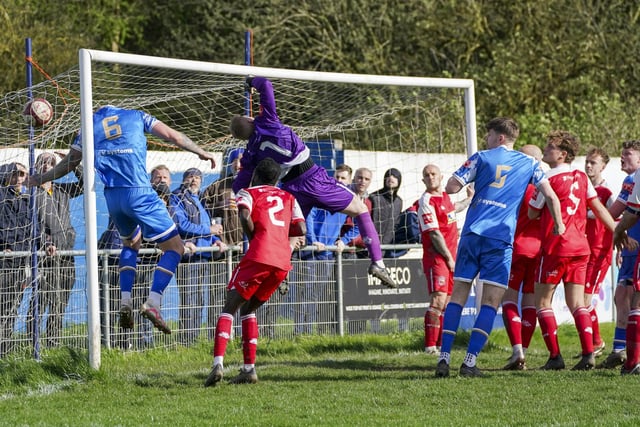 Pontefract Collieries' number six Danny Burns ends up in the net along with the ball.
