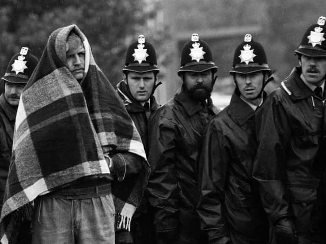 View of a striking miner, a blanket over his head against the rain, stands in front of a line of police officers  near the Orgreave coking plant, Orgreave (later renamed Waverly), Yorkshire, England, May 1984. Though the mine's colliery had been closed several years earlier, the coal plant still operated in spite of the strike. Several months later, the plant became the focal point for the most violent confrontation of the country-wide strike between police and miners, known as the 'Battle of Orgeave' (on June 18, 1984). (Photo by Tom Stoddart/Getty Images)